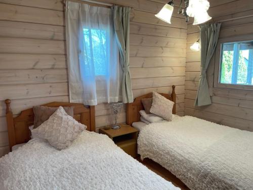 two beds in a room with wooden walls and windows at Camp inn Kiyosato GRANDEUR - Vacation STAY 42082v in Hokuto