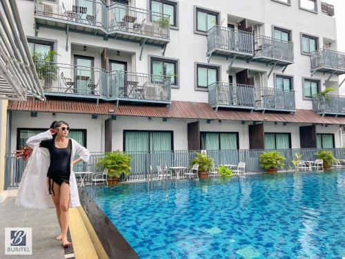 a bride standing next to a swimming pool in front of a hotel at Buritel Hotel in Buriram