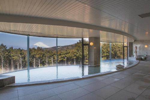 ein großes Gebäude mit einem Pool mit Bergblick in der Unterkunft Kannami Springs Hotel Kannami Glamping - Camp - Vacation STAY 62738v in Mishima