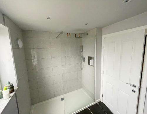a white bathroom with a shower with a white door at House in Ebbw Vale in Ebbw Vale