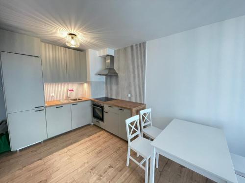 a kitchen with a table and a white table and chairs at YOURAPART Letnicka Sea in Gdańsk