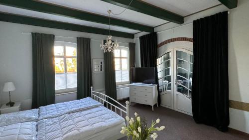 a bedroom with a bed and a tv and windows at Huus Achterdiek - Whg Anker in Dornumersiel