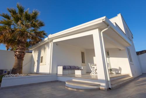 a white house with a palm tree and a couch at Villa Al Mare Guest House in Tre Fontane
