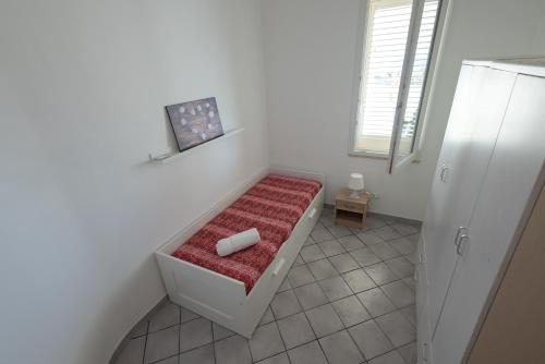 a white room with a bench with a red blanket at Villa Al Mare Guest House in Tre Fontane
