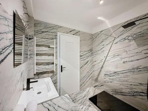 ein Badezimmer mit einem weißen Waschbecken und Marmorwänden in der Unterkunft Cosy Appartement, Lyon 6è Barrier in Lyon