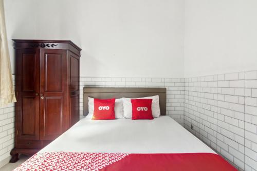una camera con un letto con due cuscini rossi di OYO 93499 Pondok Sentosa Near UPH a Giacarta
