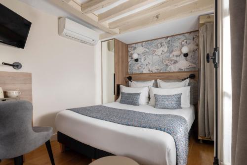 a bedroom with a large bed with blue and white pillows at Hôtel Théorème in Paris