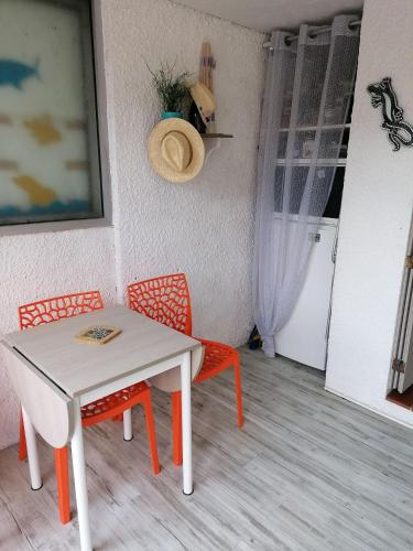 une table et deux chaises avec une table blanche, une table et des chaises dans l'établissement Maison grande terrasse proche du port St Cyprien, à Saint-Cyprien