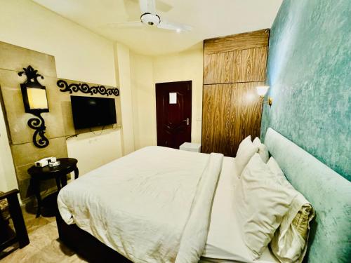 a bedroom with a white bed and a blue wall at Shelton Hotel Lahore in Lahore