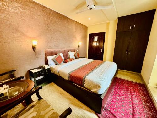 Schlafzimmer mit einem Bett, einem Schreibtisch und einem Tisch in der Unterkunft Shelton Hotel Lahore in Lahore