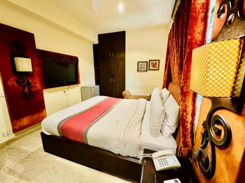 a hotel room with a bed and a television at Shelton Hotel Lahore in Lahore