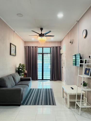 a living room with a couch and a ceiling fan at Aina Guest House in Kota Bharu