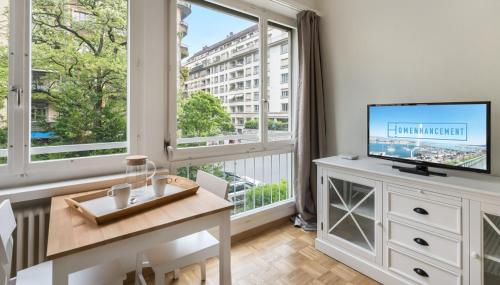 uma sala de estar com televisão e uma grande janela em Athénée 40 Residence by Homenhancement em Genebra