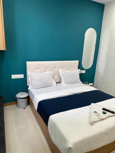 1 dormitorio con 2 camas y pared azul en Hotel sky palace adajan, en Surat
