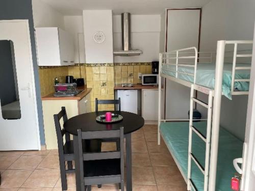uma pequena cozinha com uma mesa e um quarto com beliches em Grand studio 4 50m de la plage pour 4 em Argelès-sur-Mer