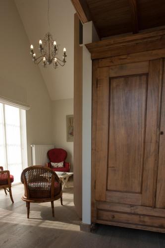 a living room with a wooden door and a chandelier at Domein Het Weiland in Damme