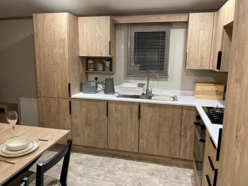 una cocina con armarios de madera y una mesa con fregadero en The Drey, en Grantown-on-Spey