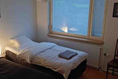 Una cama con una toalla en una habitación con ventana en Cozy completely renovated flat (sis. Alv), en Kajaani