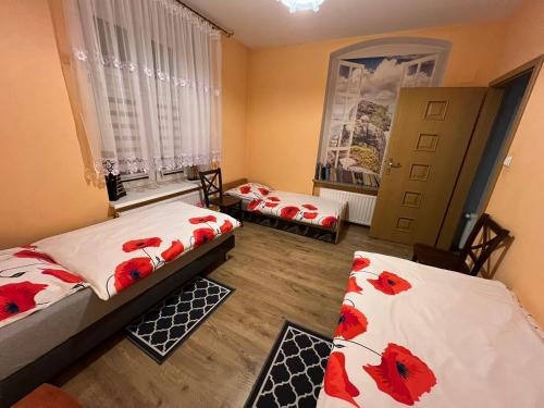 two beds in a room with red flowers on them at Apartament Kudowa Zdrój - Słone 60m2 in Kudowa-Zdrój