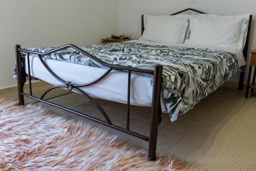 a bed with a metal frame and a rug at Stavroula's Houses in Kélla