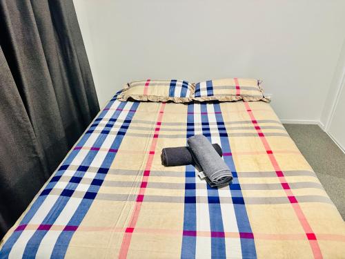 a bed with a plaid blanket on it with a flashlight at Private Double Room in Christchurch