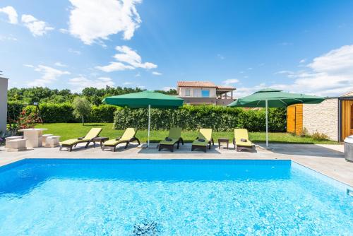 een zwembad met ligstoelen en parasols bij Villa Fantasia for 8 people with jacuzzi and private pool in Hreljići