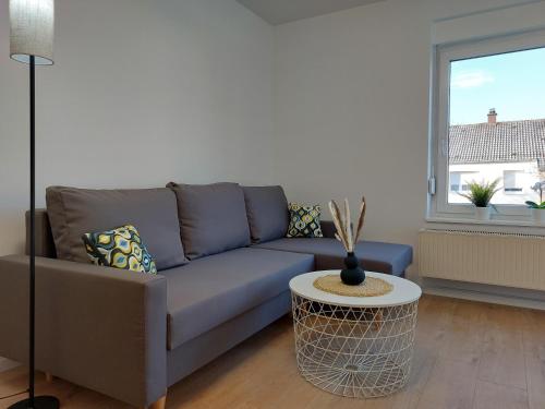 a living room with a blue couch and a table at Deluxe Apartment 3 P I 2 SZ I Balkon I Küche in Oberkochen - Hensold, Zeiss fußläufig in Oberkochen