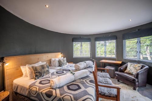 a bedroom with a bed and a chair and windows at A Stone's Throw Accommodation in Grahamstown
