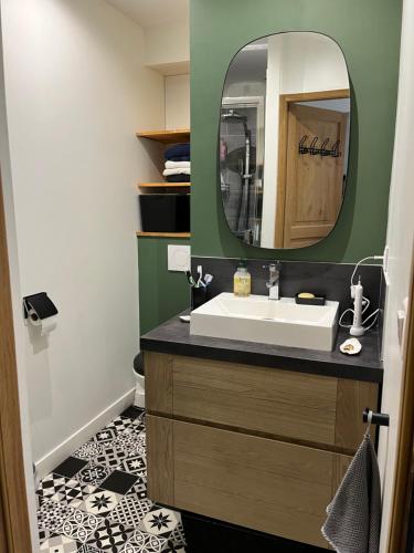 une salle de bain avec un lavabo et un miroir dans l'établissement Rayon de soleil, à La Baule