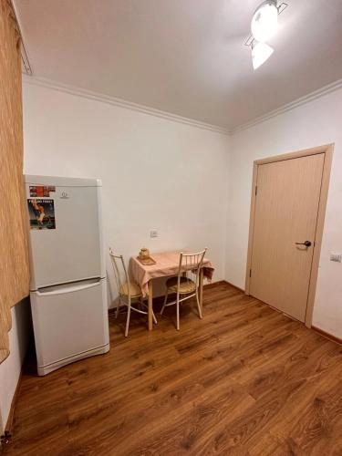 eine Küche mit einem Tisch und einem weißen Kühlschrank in der Unterkunft Мухамедханова in Taldykolʼ