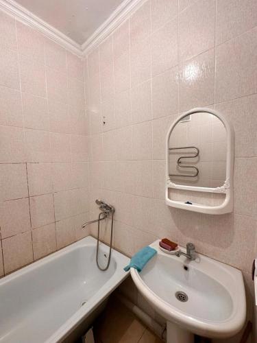 ein Badezimmer mit einem Waschbecken, einer Badewanne und einem Spiegel in der Unterkunft Мухамедханова in Taldykolʼ