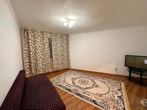 ein Wohnzimmer mit einem Sofa und einem TV in der Unterkunft Мухамедханова in Taldykolʼ