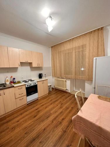 eine Küche mit Holzschränken und einem weißen Kühlschrank in der Unterkunft Мухамедханова in Taldykolʼ