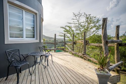 a wooden deck with chairs and a table and a window at A Stone's Throw Accommodation in Grahamstown