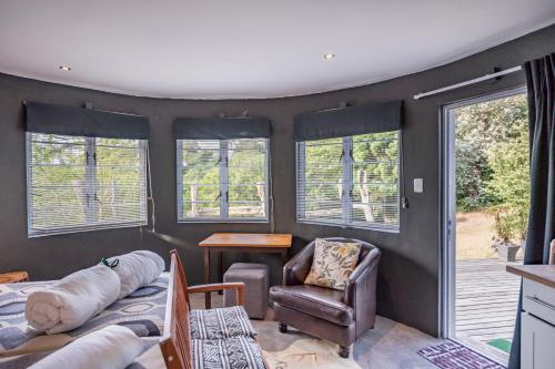 a living room with a couch and a chair and windows at A Stone's Throw Accommodation in Grahamstown