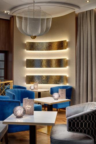 a lobby with blue chairs and tables and a chandelier at Ensana Nové Lázně in Mariánské Lázně