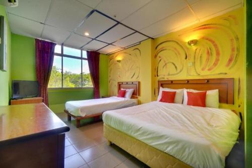 um quarto de hotel com duas camas e uma televisão em DJ Hotel Lumut em Lumut