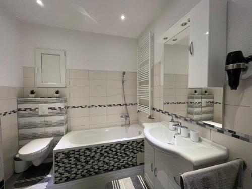 a bathroom with a tub and a sink and a toilet at Maria's Ferienwohnung - Modernität trifft Eleganz in Dettingen an der Erms