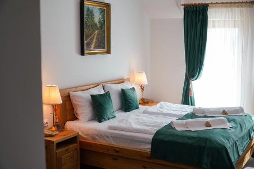 a bedroom with a bed with green and white pillows at Paleus Resort in Oradea