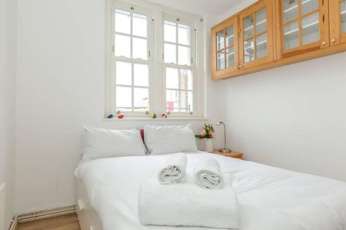 1 dormitorio con 1 cama blanca y 2 toallas en Central 1 BR Apartment *Zone 1* Elephant and Castle, en Londres