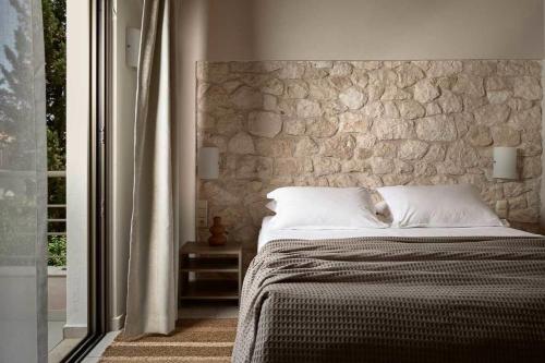 a bed in a bedroom with a stone wall at Avesta Private Villas - Kallisto in Vlikhon