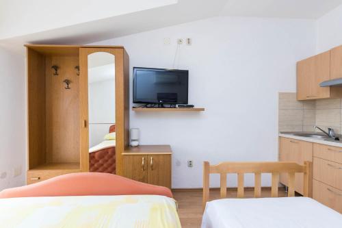 a room with a kitchen with a tv and a bed at Apartments Cipetic in Kaštela