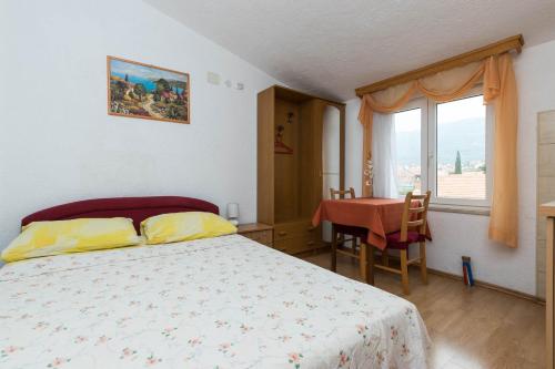 a bedroom with a bed and a table and a window at Apartments Cipetic in Kaštela