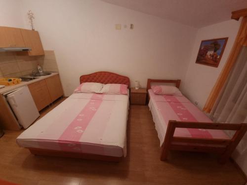 two beds in a small room with a kitchen at Apartments Cipetic in Kaštela