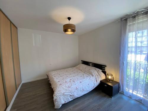 une chambre avec un lit, une lampe et une fenêtre dans l'établissement Bel appart avec terrasse tout proche plage, à Saint-Cyprien