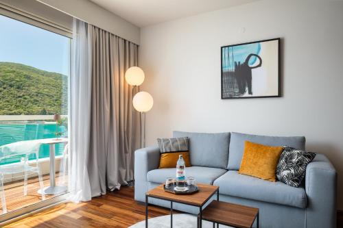 a living room with a blue couch and a large window at Boutique Hotel Adoral in Rabac