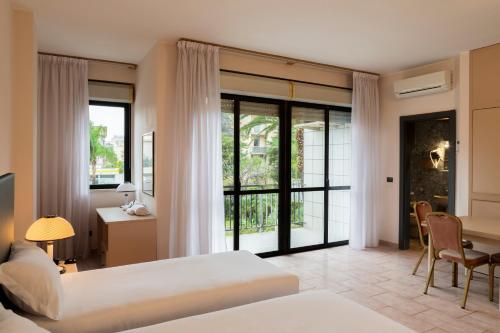 una camera d'albergo con 2 letti, una scrivania e un tavolo di B&B HOTEL Bari Rondò a Bari