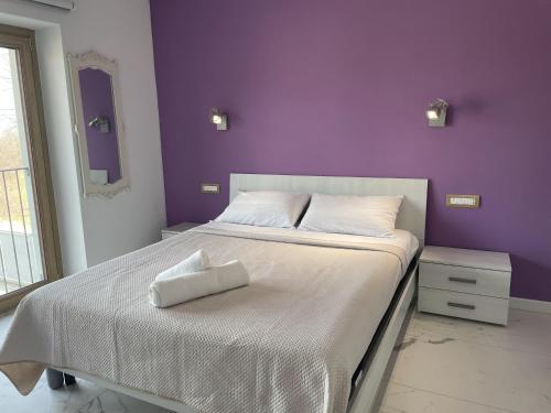 a bedroom with a white bed with a purple wall at Le Ghie in Mondovì