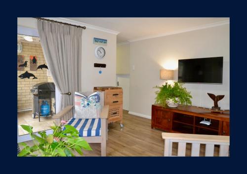 a living room with a flat screen tv and a couch at Rest and Sea Self-catering - The perfect family or couples getaway to relax and refresh in Franskraal