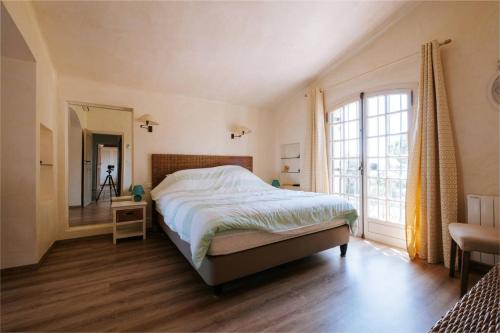 een slaapkamer met een bed en een groot raam bij La Villa des Cades avec vue mer et piscine privée sur les hauteurs de Stre-Maxime in La Nartelle